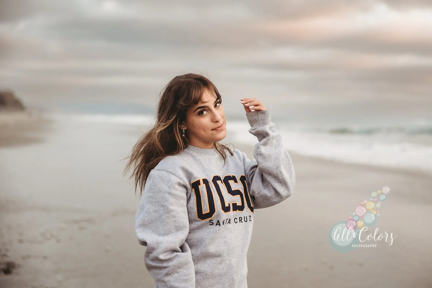 High School Senior wearing a hoodie from UC Santa Cruz at the beach