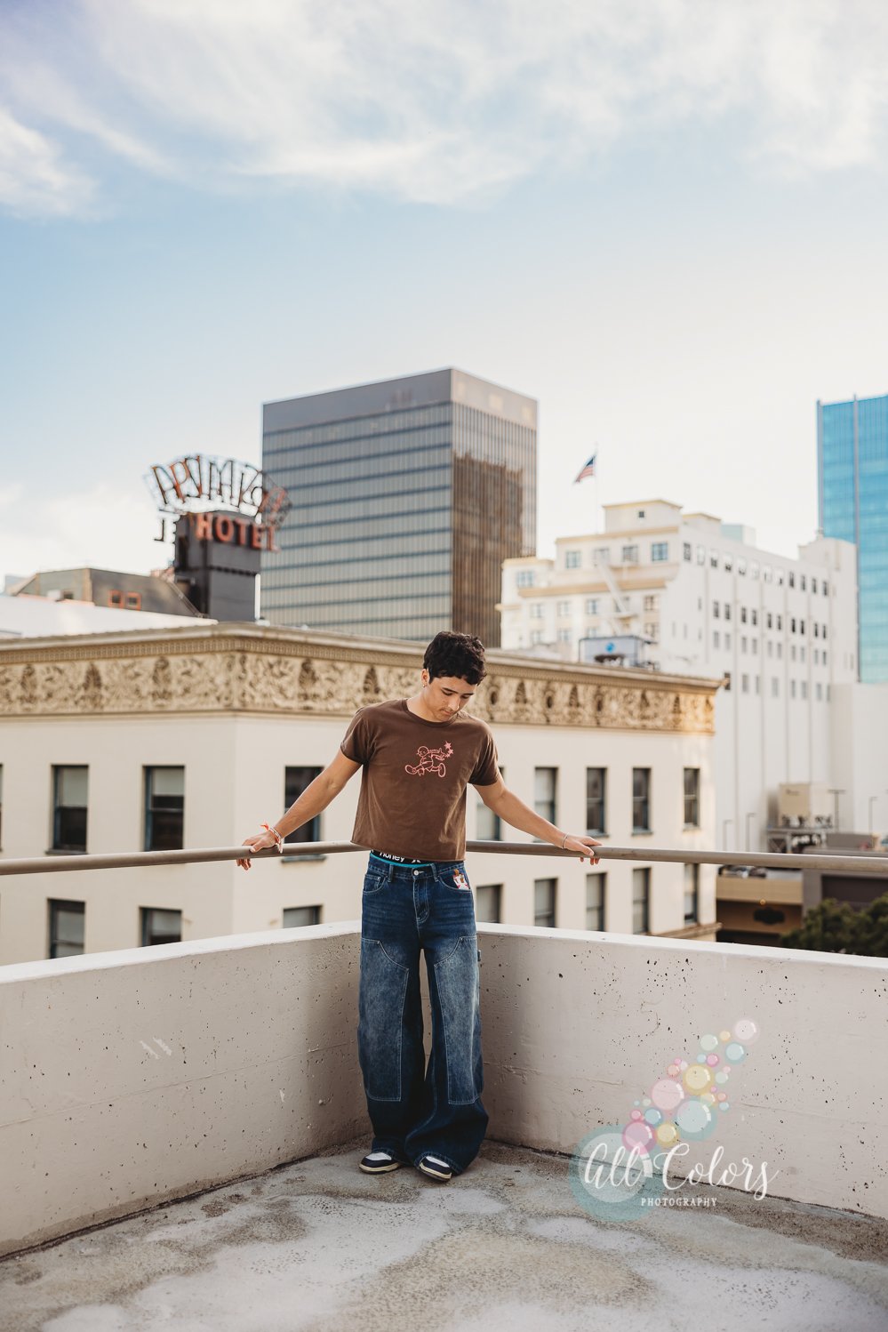 Teenage boy on a roof top with downtown buildings behind him.