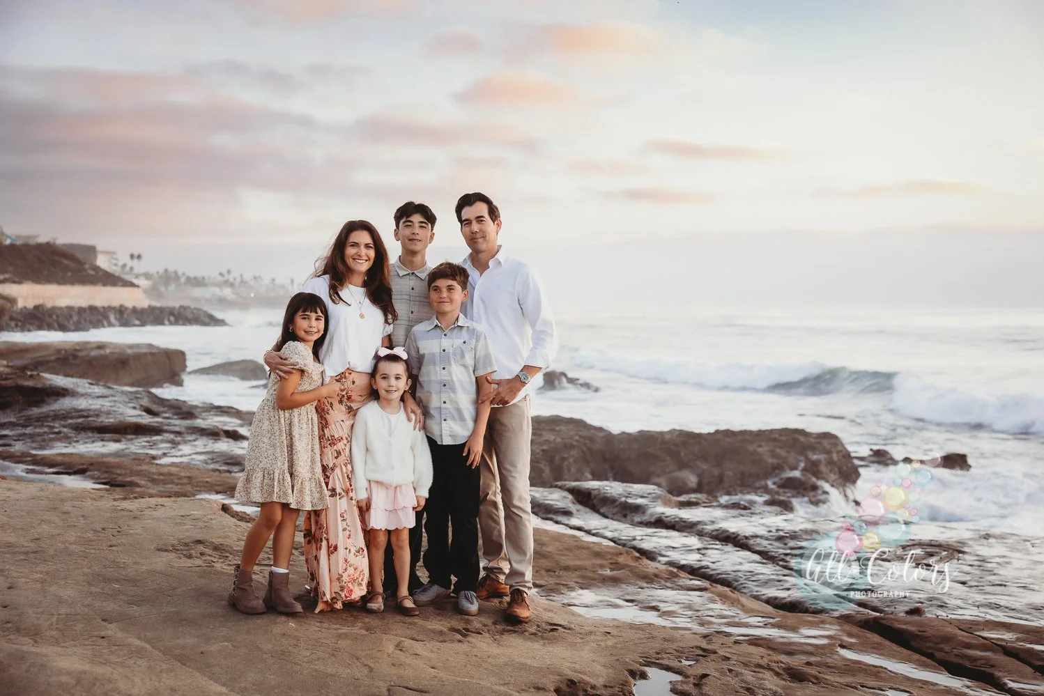 Family of mom, dad and four kids photo on the beach cliffs in San Diego.