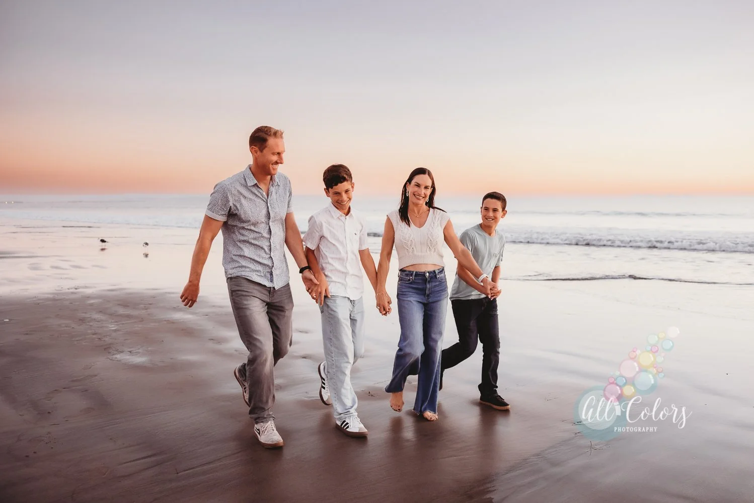 Family of four walking on the beach holding hands