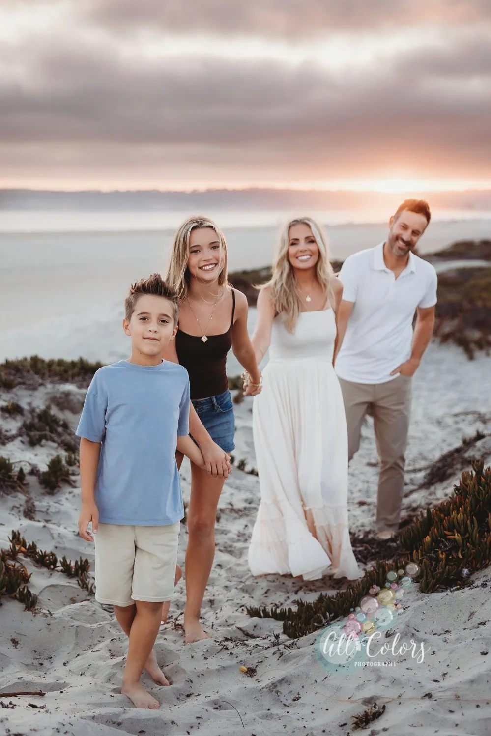 Family of 4 wearing muted colors walking on the dunes of Coronado.