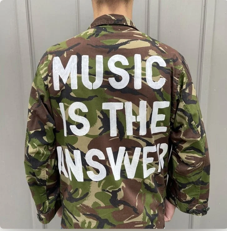 the back of a camouflage jacket with the word music is the answer