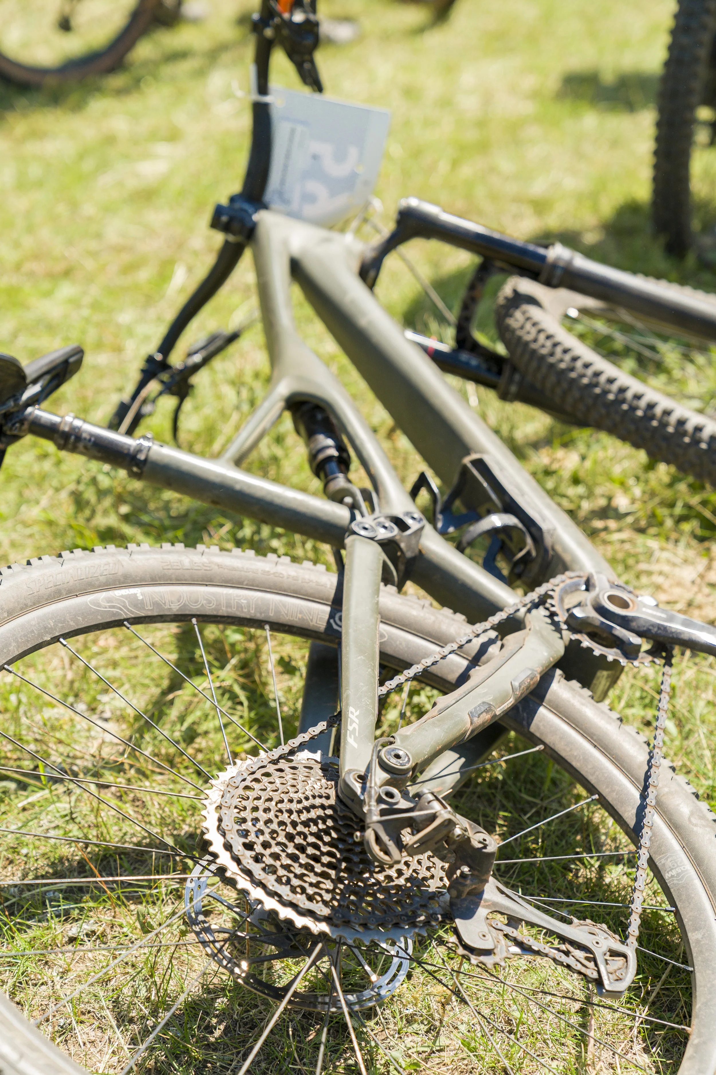 A fallen mountain bike lying on grass with the chain and rear derailleur visible.