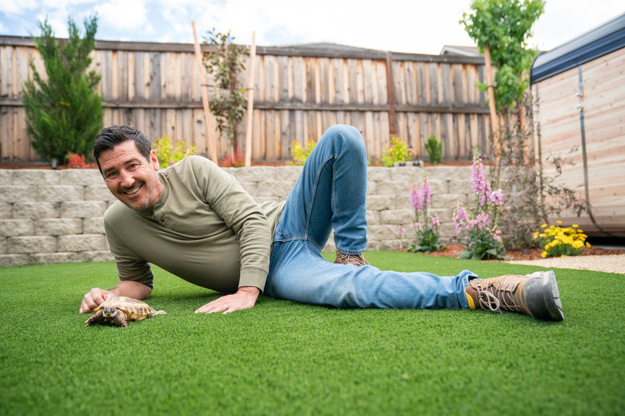 HGTV host Jonathan Knight relaxing on the pet-friendly synthetic lawn with the family tortoise after the backyard transformation