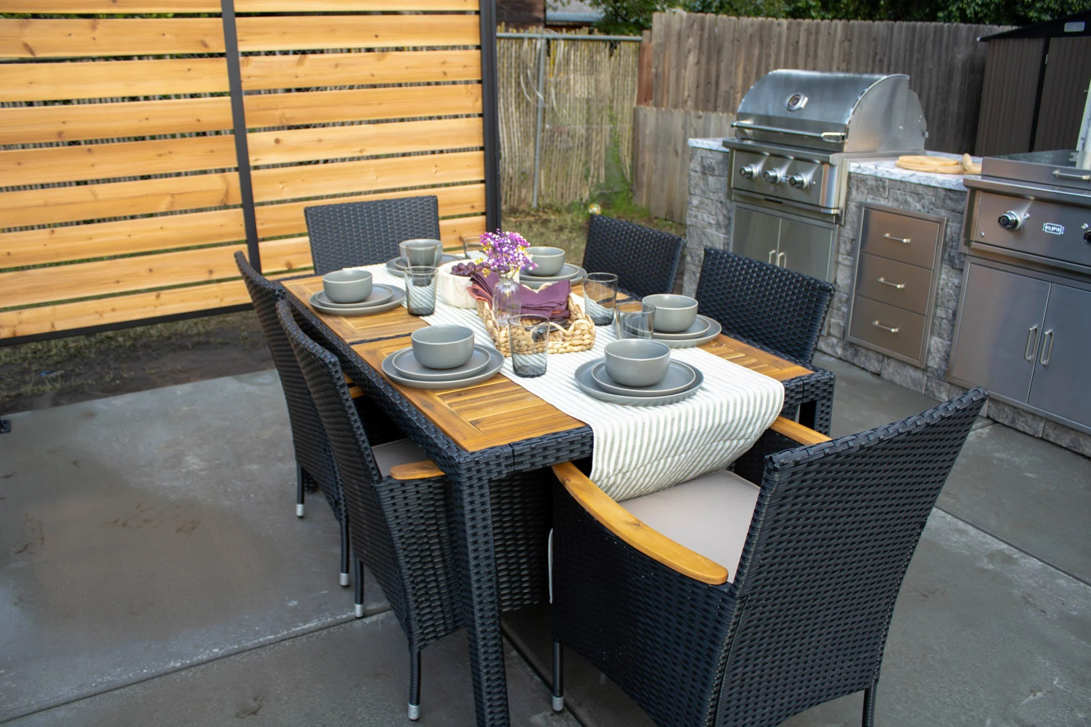 Outdoor dining set for the family beside the warm cedar and steel privacy screen.