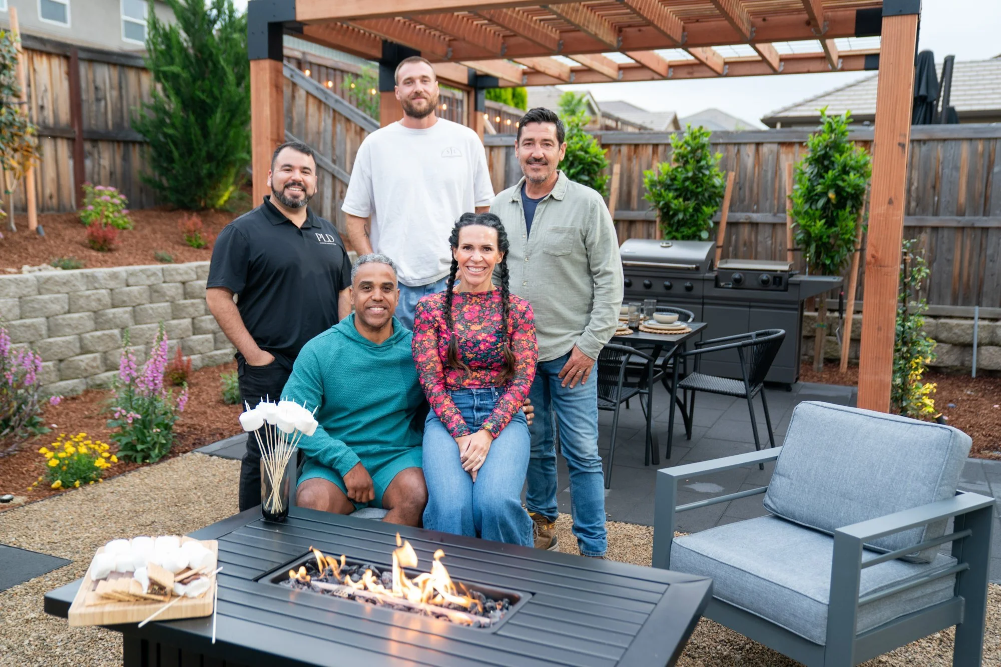 Landscape designer Matthew Vasquez with host Jonathan Knight, the build team, and the homeowners at the fire pit reveal of HGTV's Crashers episode 4