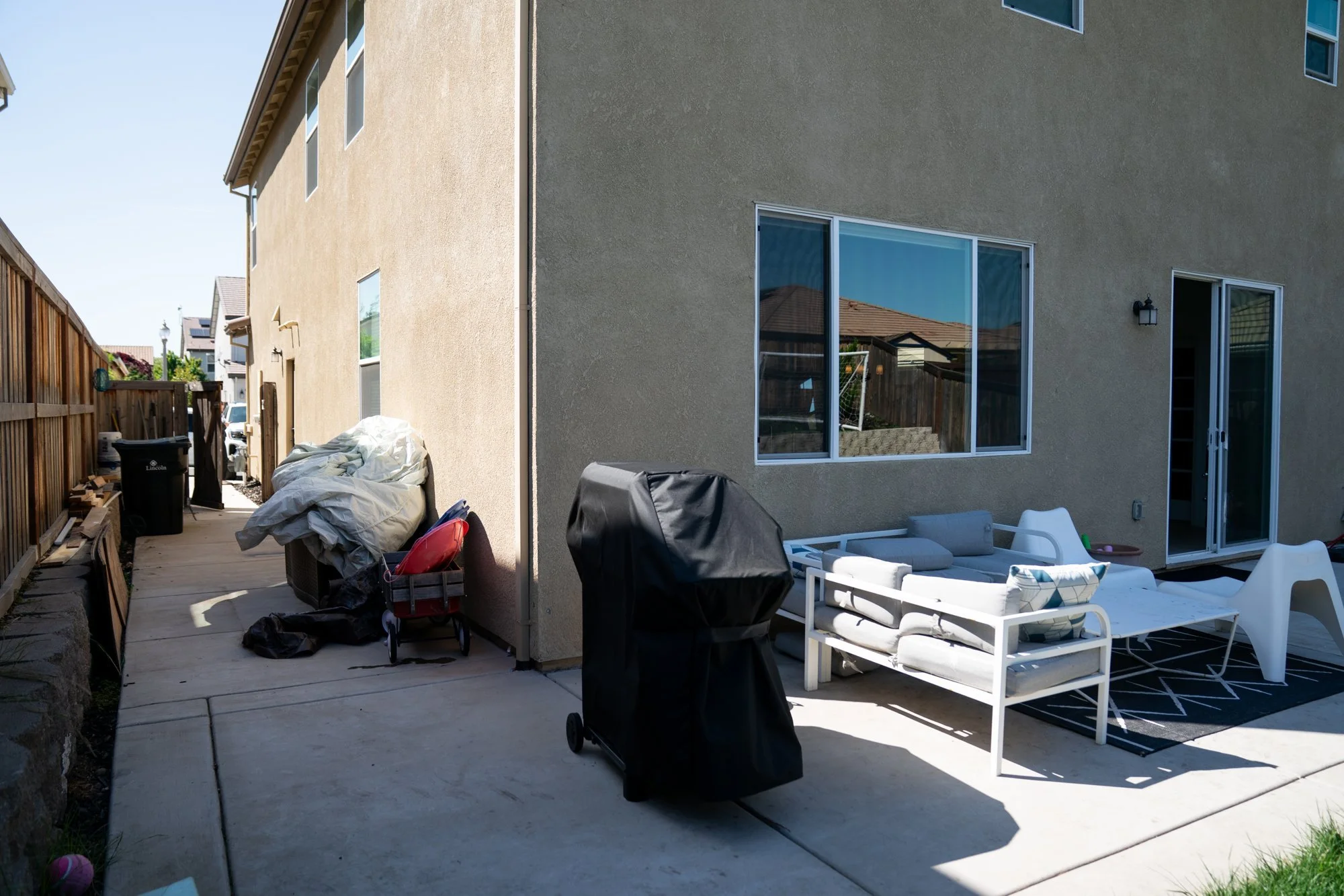 Before: unused side patio with scattered furniture ahead of the 72-hour HGTV Crashers backyard makeover
