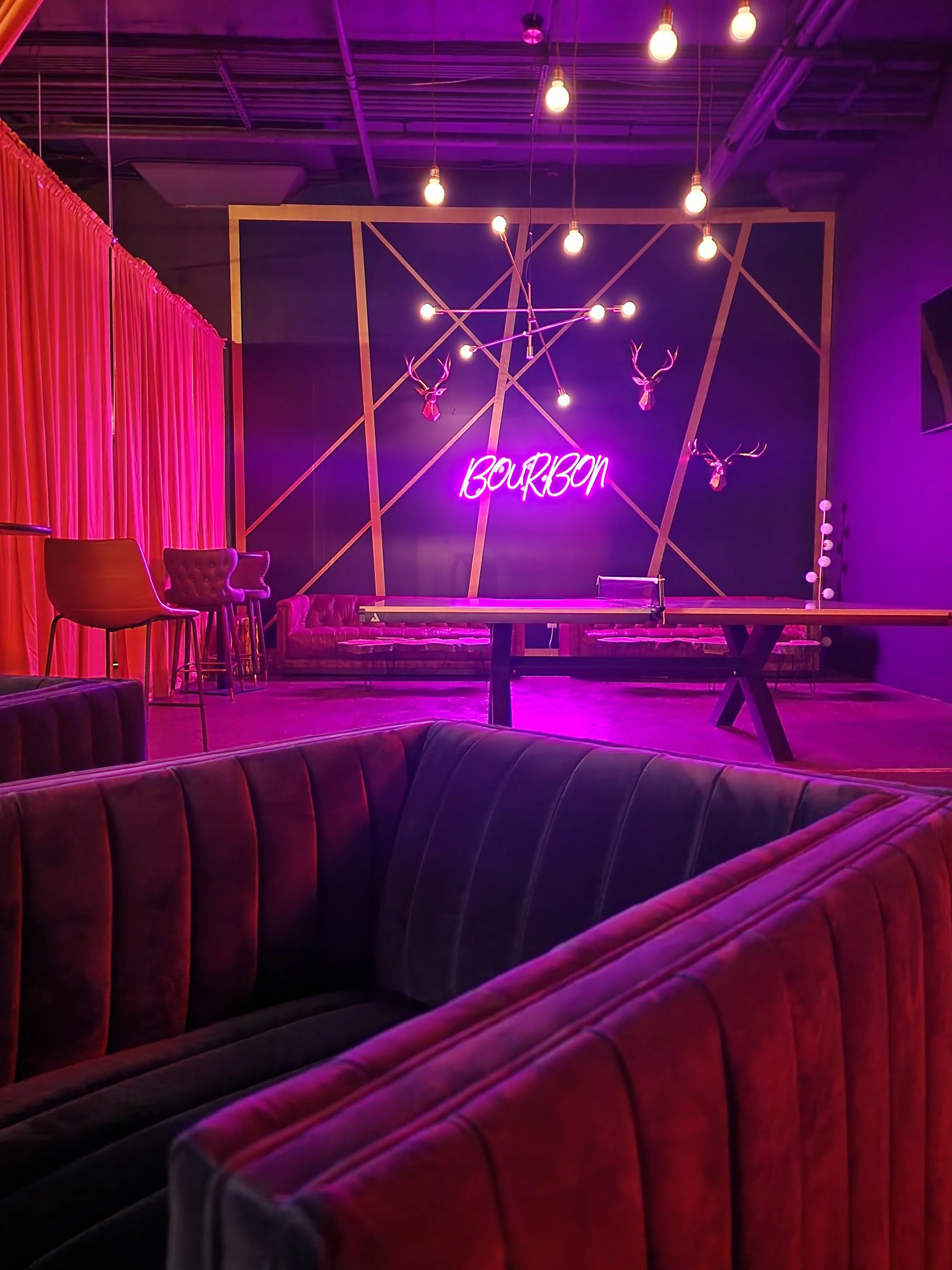 Private event lounge at District 7 Social Hall in Lexington, featuring velvet seating, ping pong, dramatic neon lighting, and a stylish bourbon-inspired atmosphere.