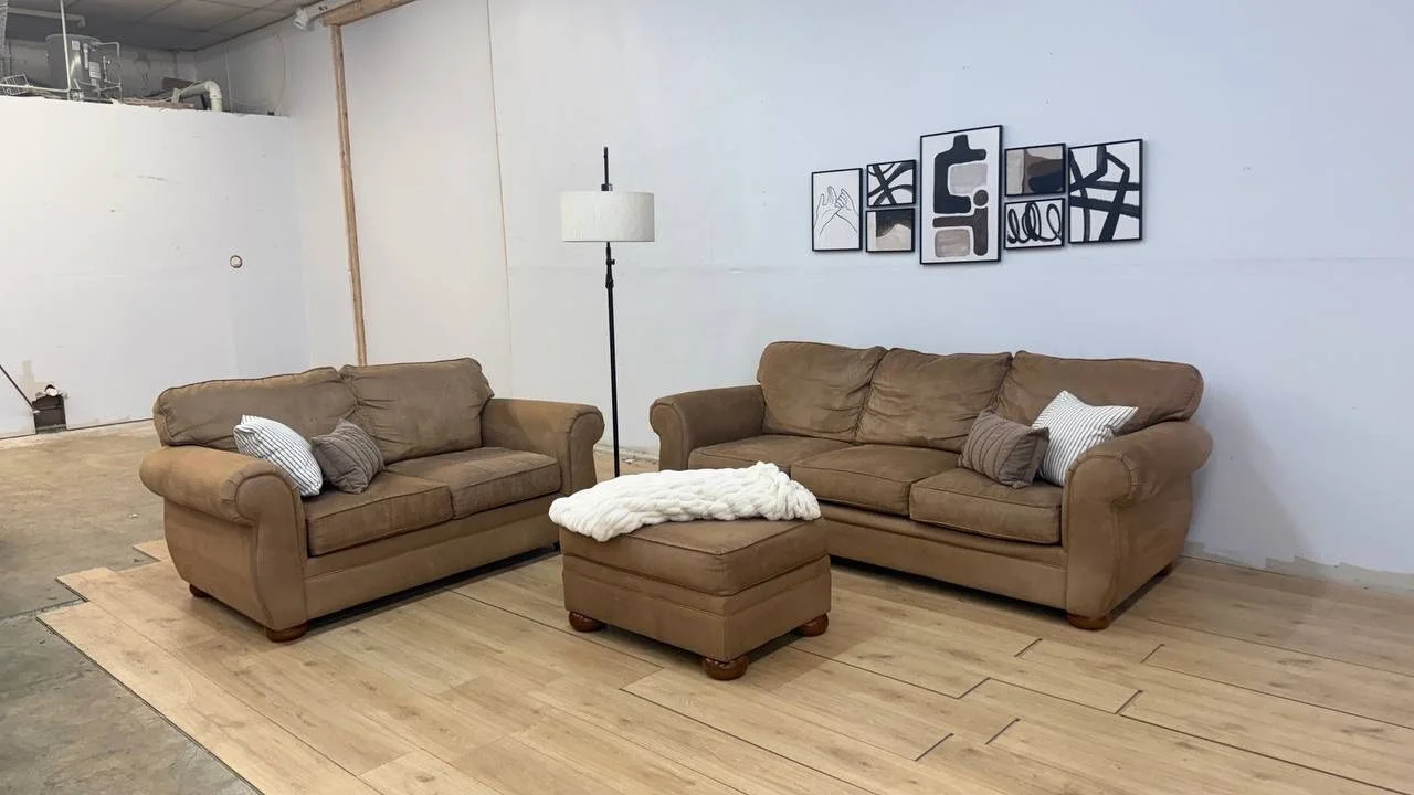 Living room with two beige sofas, a matching ottoman with a white blanket, a floor lamp, and black and white abstract wall art.