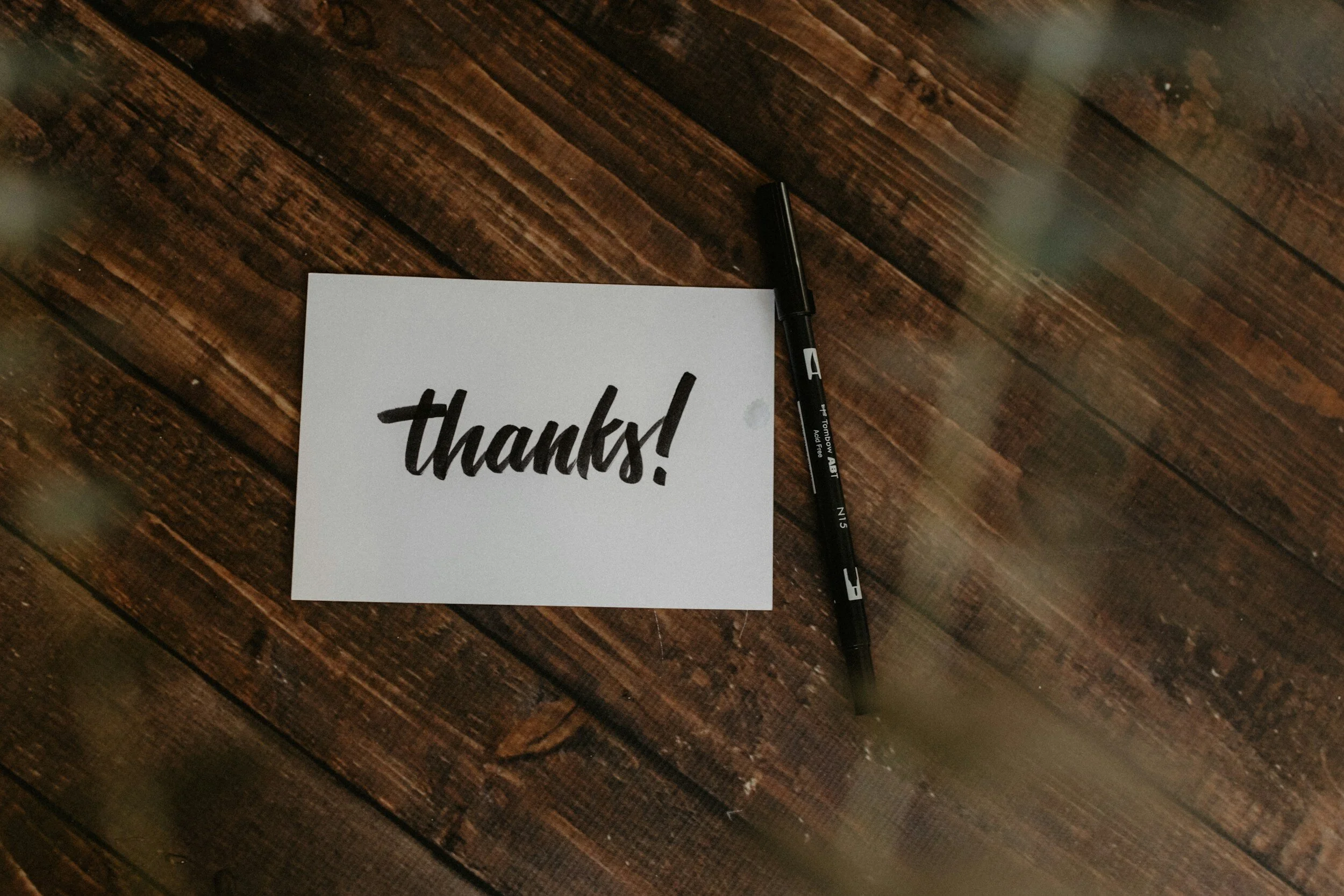 "Thanks!" card on wooden table with black marker pen