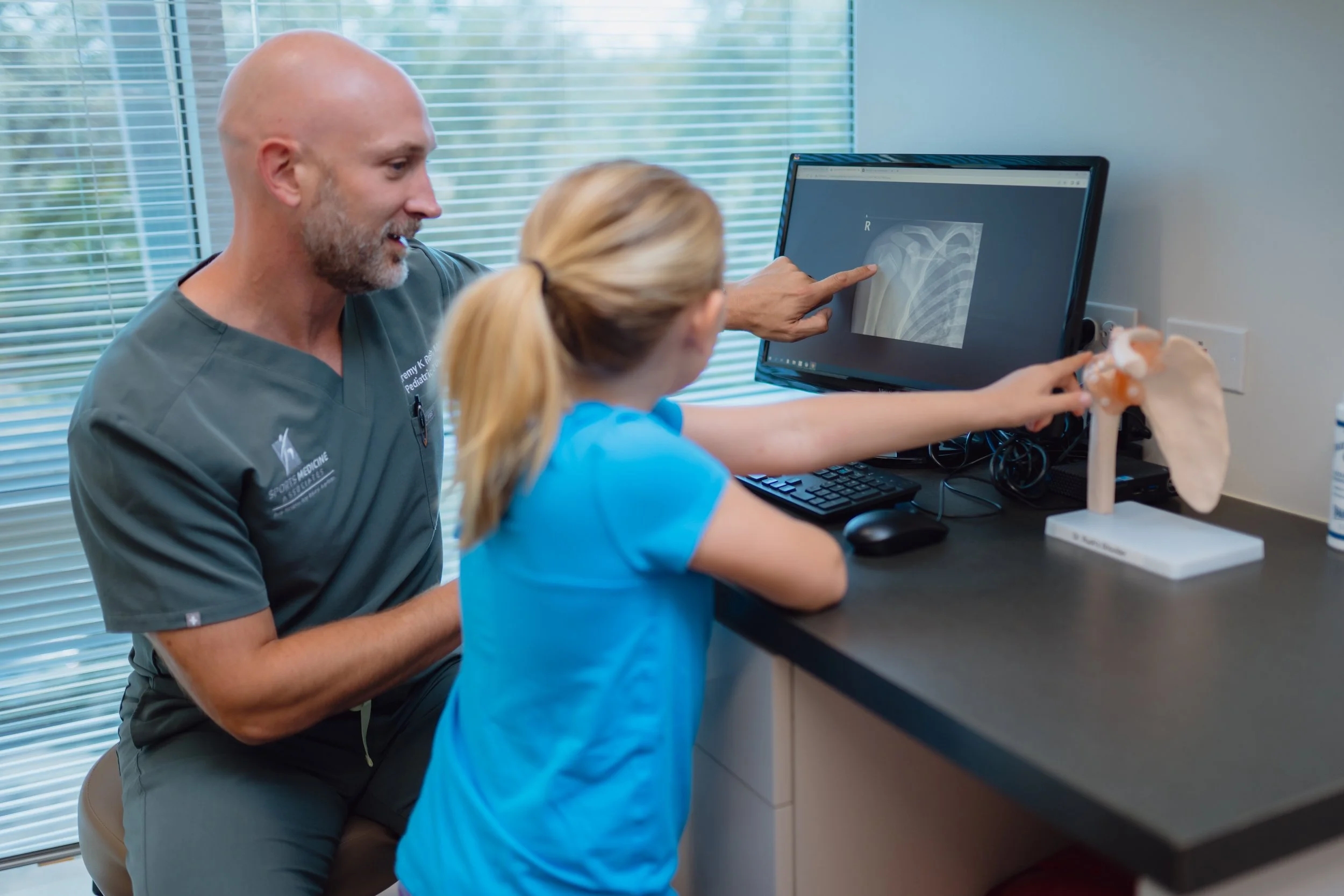 Sports medicine doctor, Dr. Rush in San Antonio assessing shoulder pain in a young athlete.