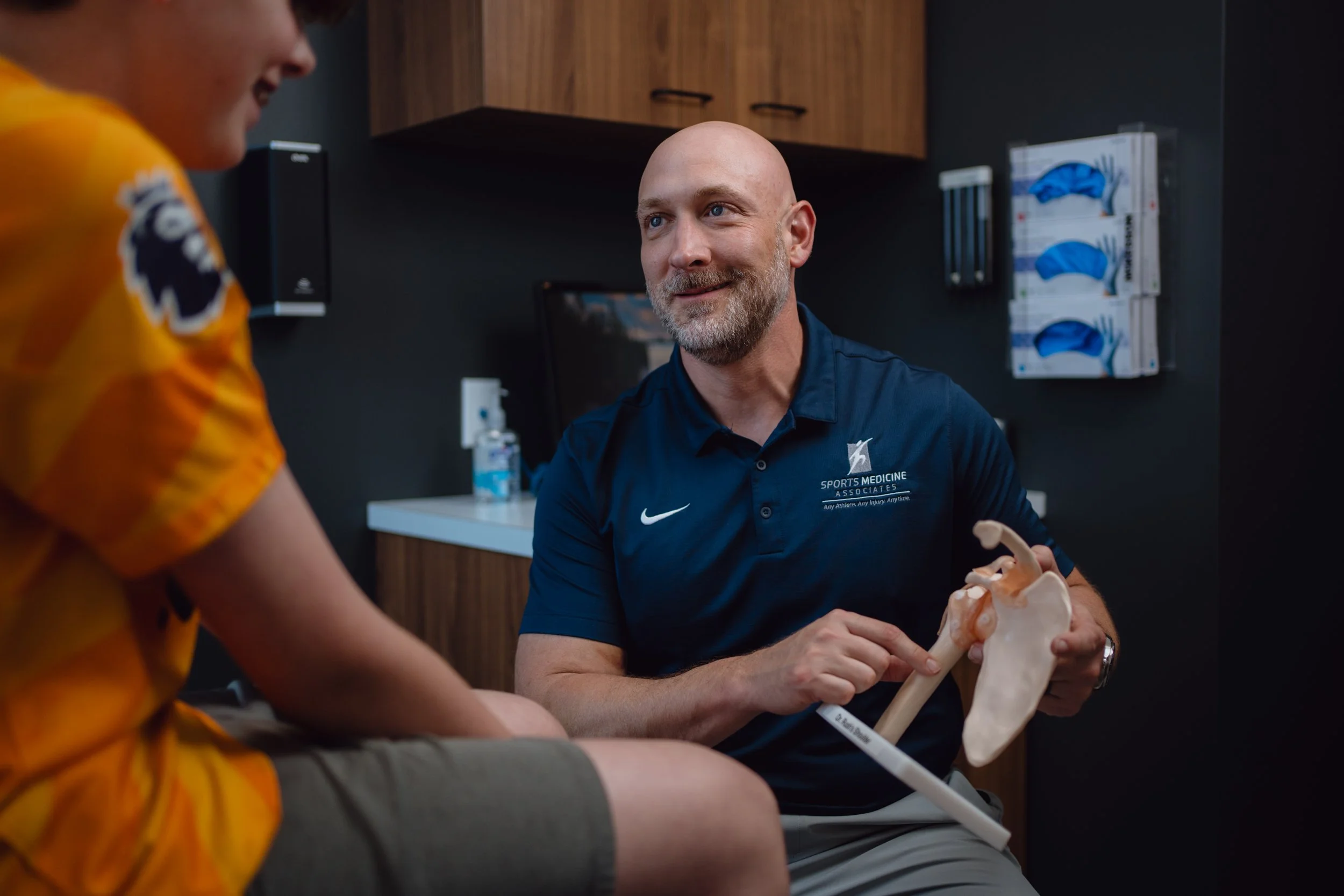 Sports medicine doctor in San Antonio assessing shoulder pain in a high school baseball player.