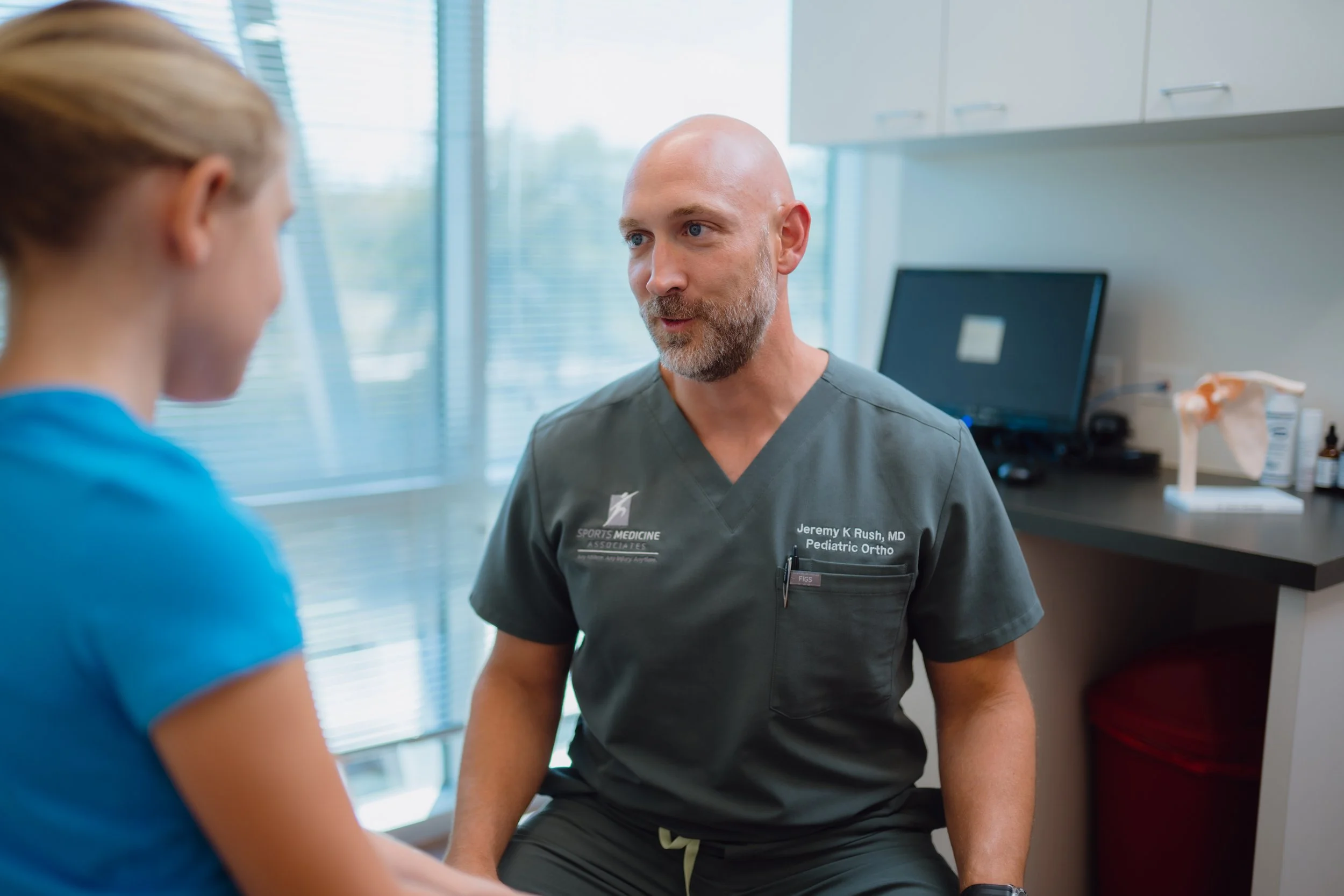 Dr. Jeremy Rush, sports medicine doctor in San Antonio, examining a young athlete’s knee injury.