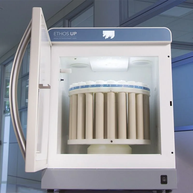 A medical sterilizer machine with a transparent door, labeled 'ETHOS UP', containing test tubes filled with liquid, likely used for sterilizing laboratory samples.