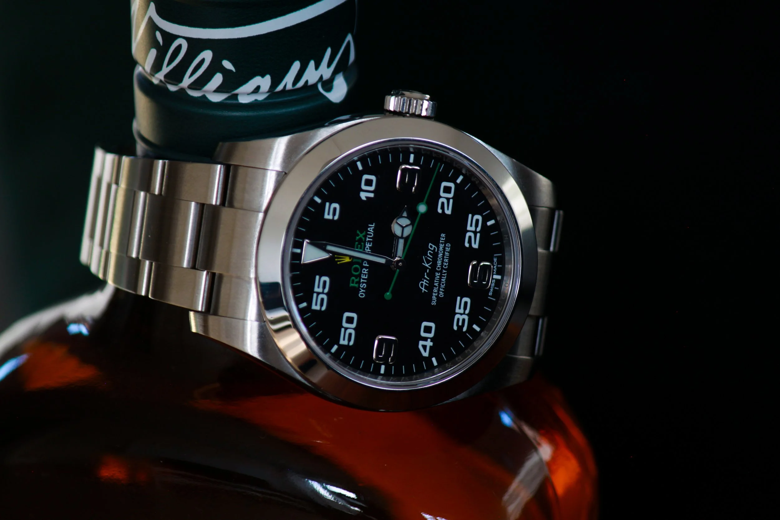 Et Rolex Oyster Perpetual Air-King ure i rustfrit stål med sort urskive, sat på en refleksiv overflade.