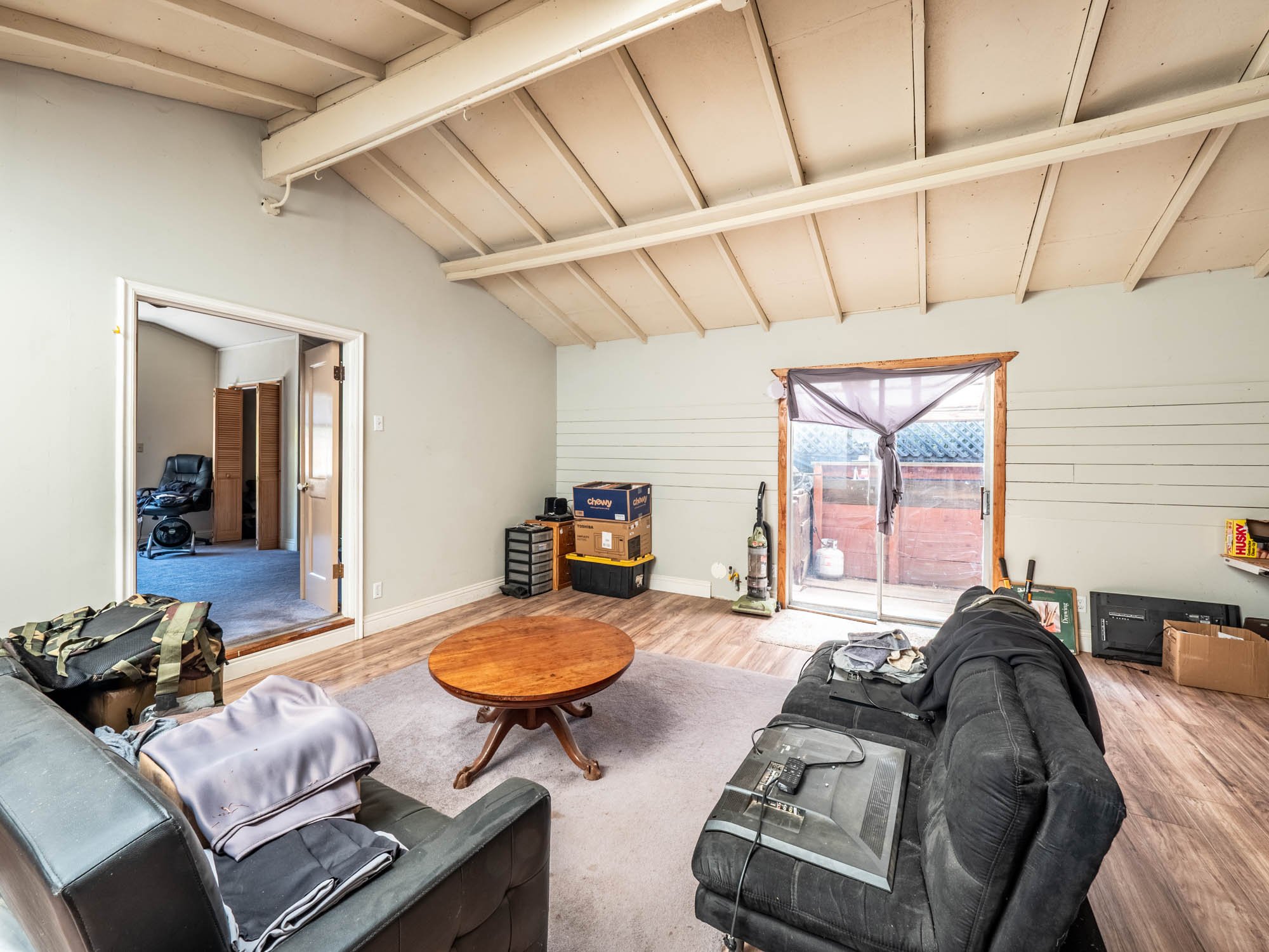 The interior of the ADU is simple and spacious, with a vaulted ceiling and natural light streaming into the living area and bedroom. Clean lines, neutral walls, and basic finishes create a blank canvas for any style.