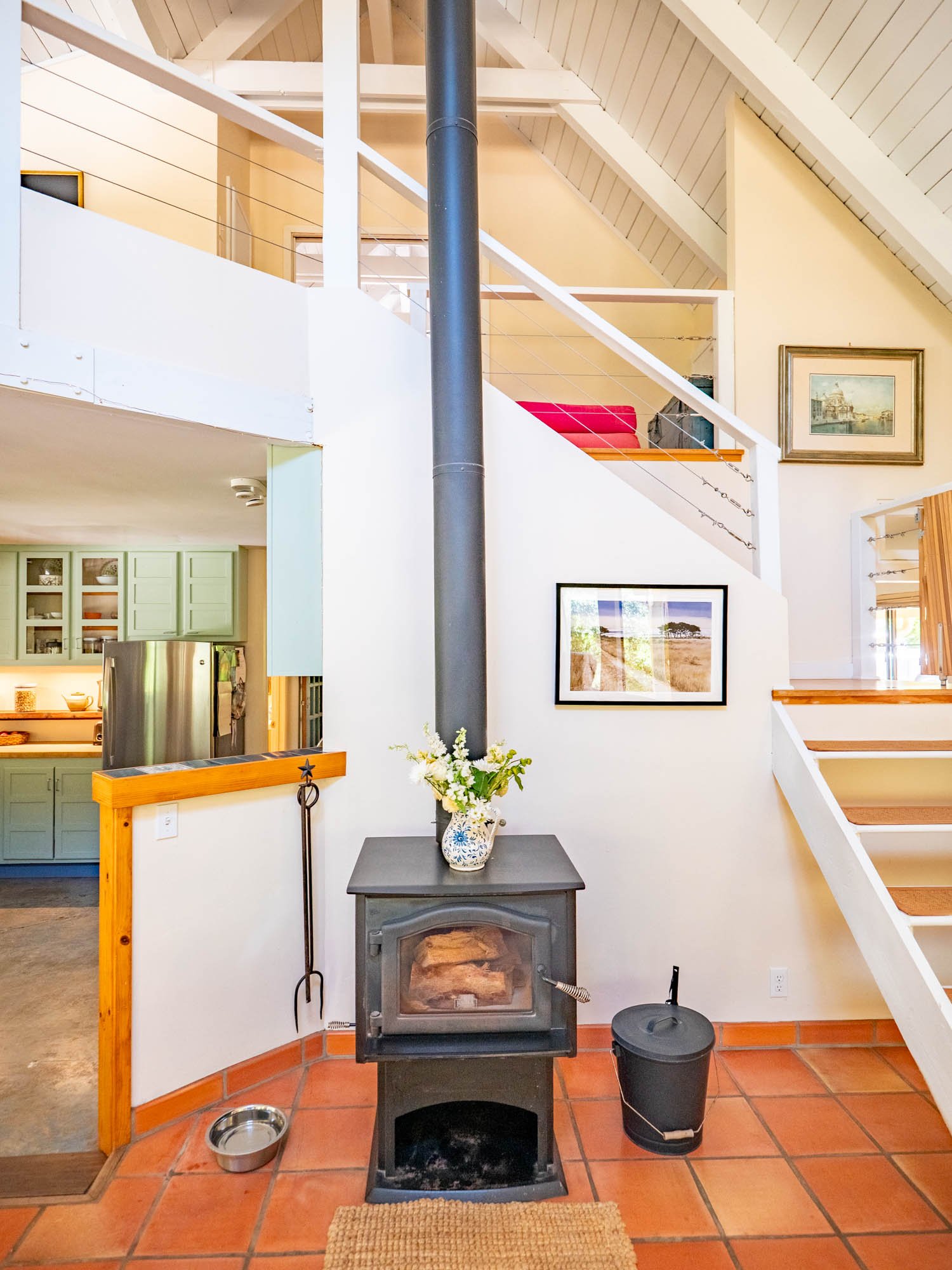 A freestanding wood stove anchors the space, adding both physical warmth and visual coziness.