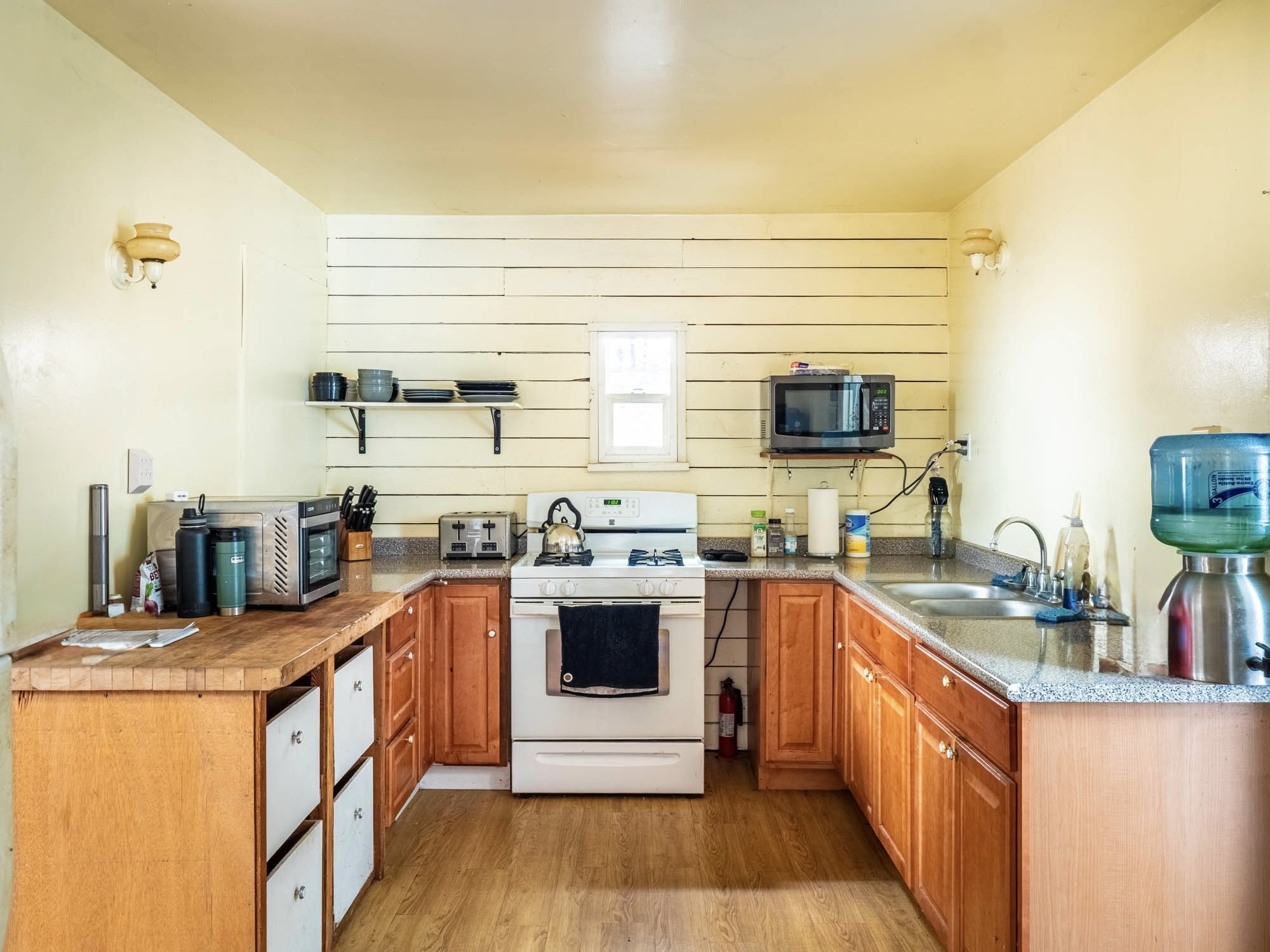 The ADU kitchen is cozy and country-inspired, featuring a mix of open shelving, wood countertops, and classic cabinetry.