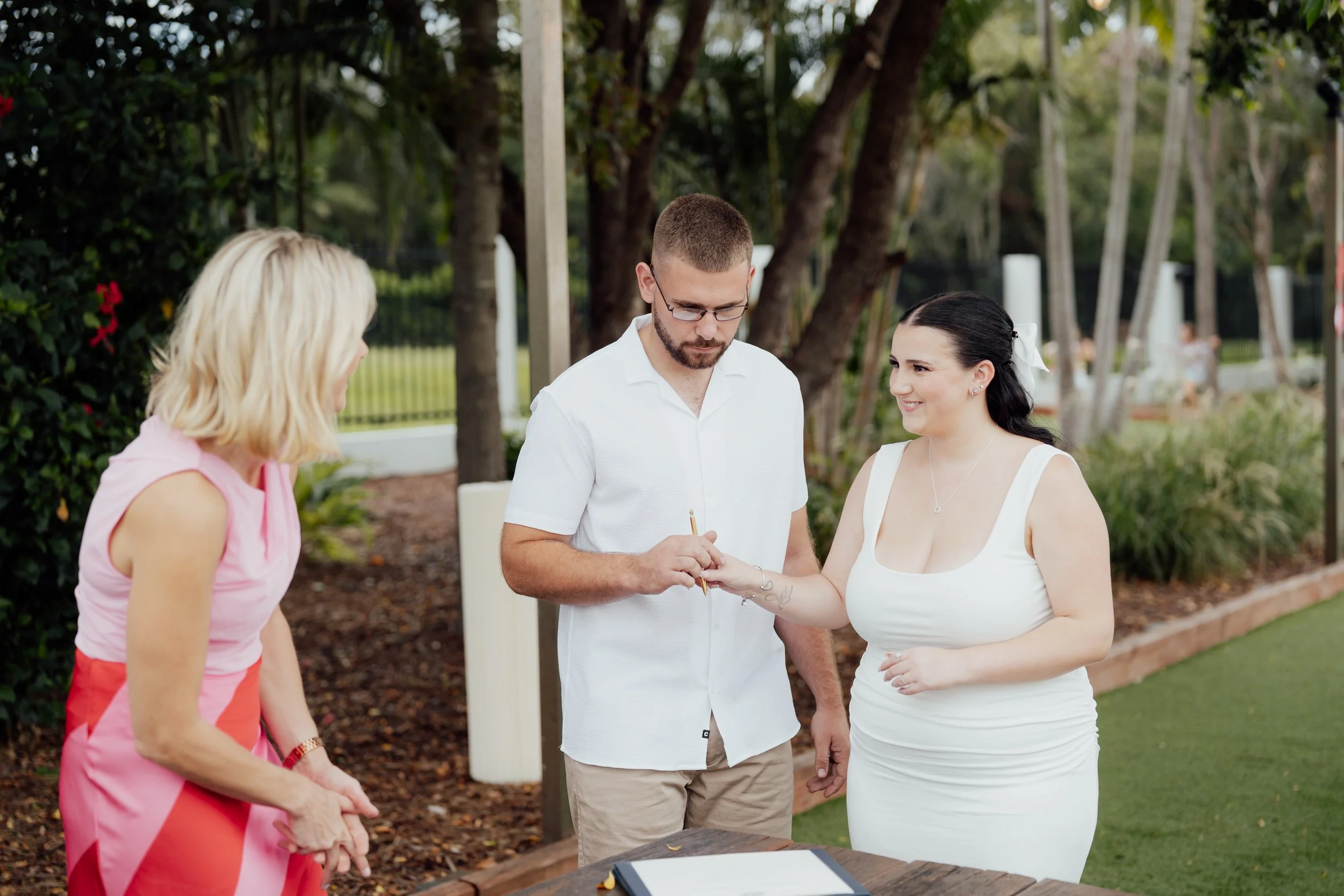 Couple signing their marriage papers at a legals only marriage ceremony in the beer garden of the Bateau Bay Hotel on the NSW Central Coast with celebrant Bec Page The Love Page. Wedding photo taken by Jacob Hughes Photography