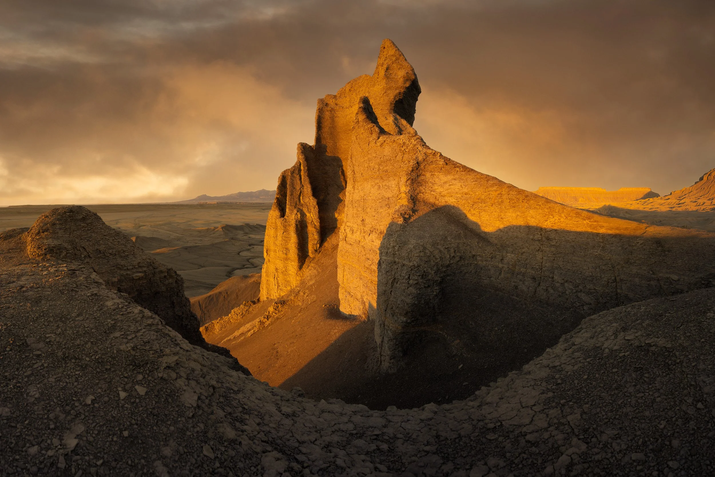 First light ignites a jagged clay fin above cracked badlands near Factory Butte, Utah.
