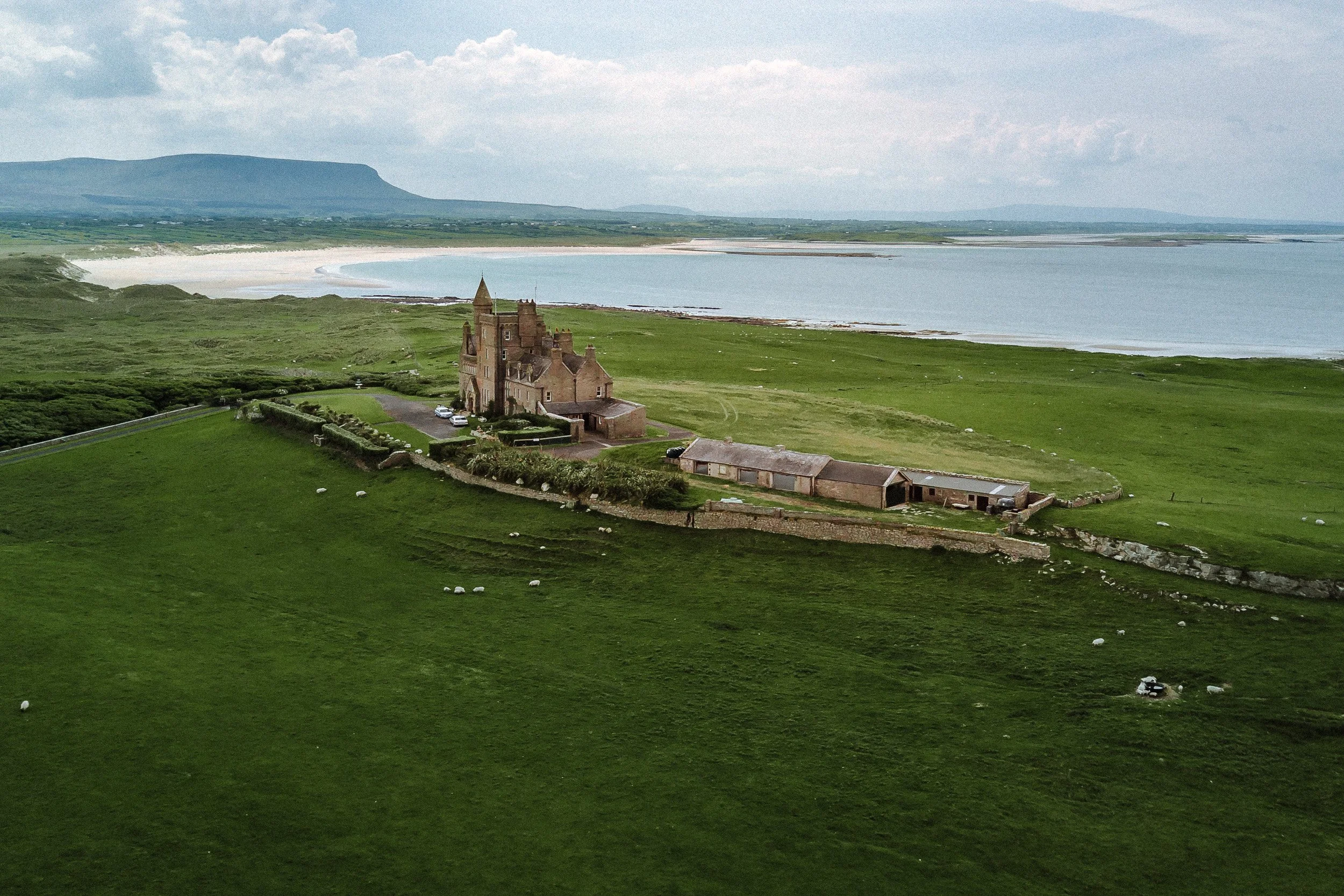 Classiebawn Castle stands alone on green headland pasture at Mullaghmore, with Benbulben rising across the bay, County Sligo, Ireland.