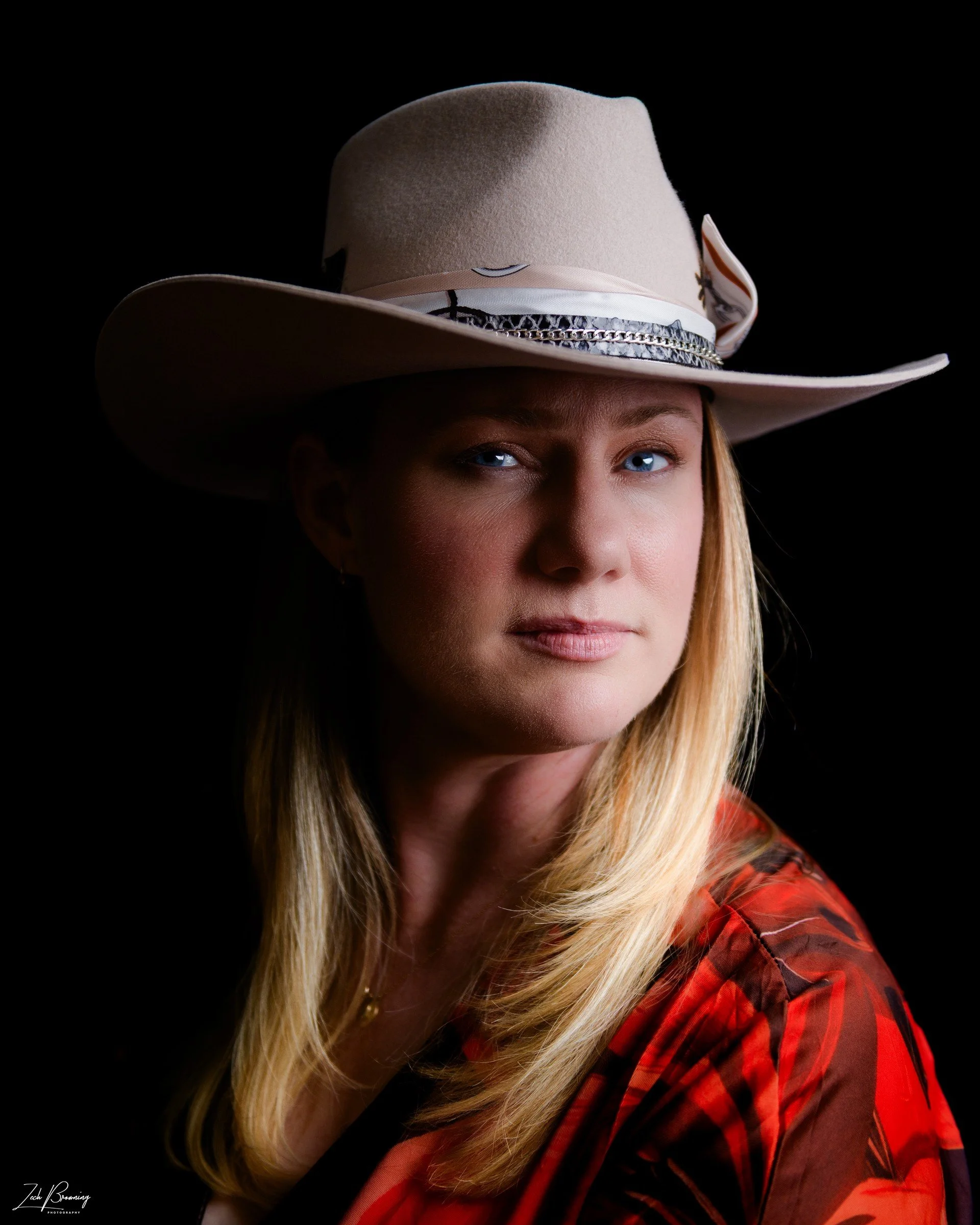 Penny Lee Browning, lyricist of The Tales of Pistol Smoke and Roses, wearing a cowboy hat and red blouse.