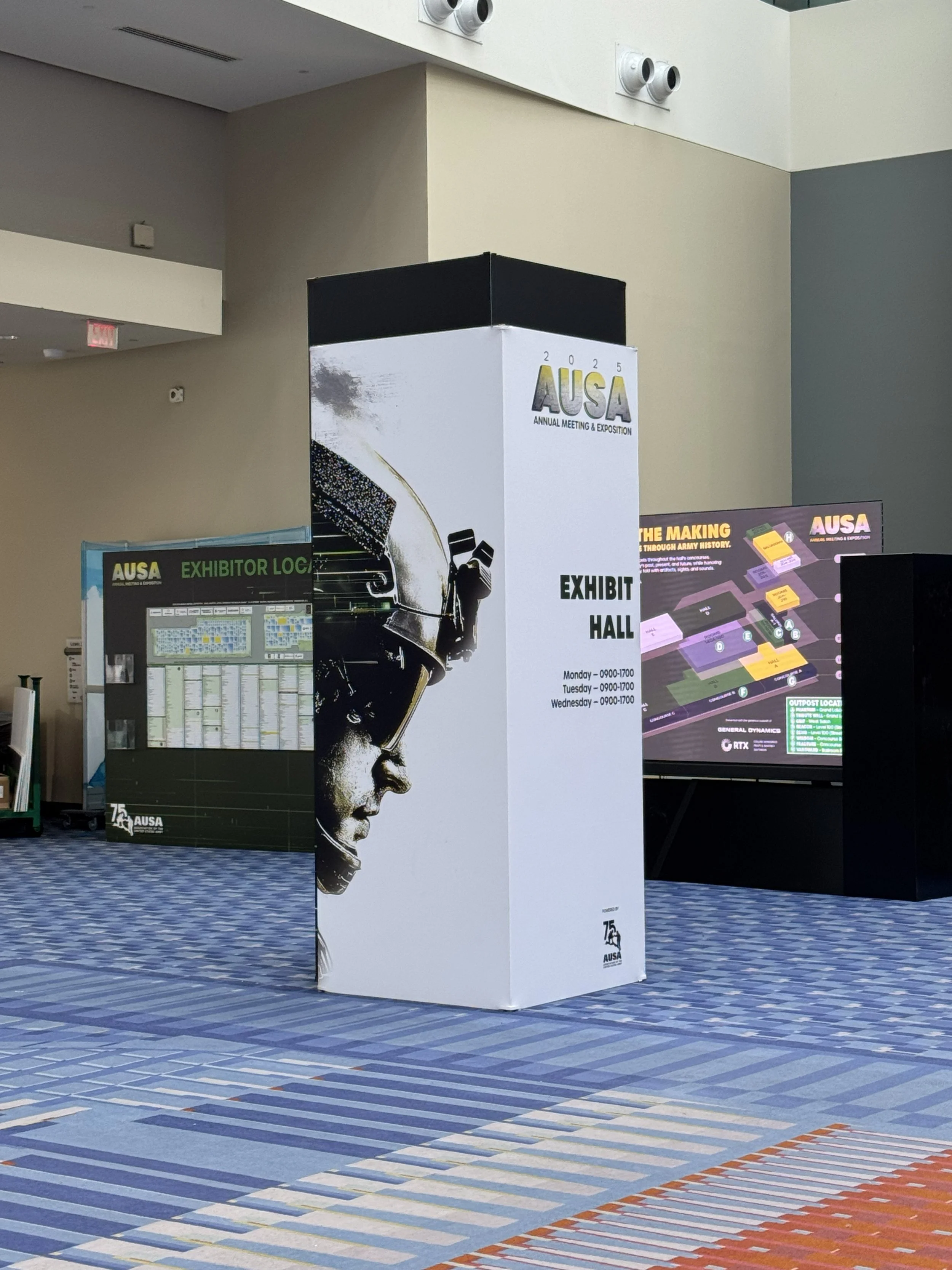Exhibit hall banner for AUSA Annual Meeting & Exposition 2025 with a profile of a soldier wearing goggles and headphones.