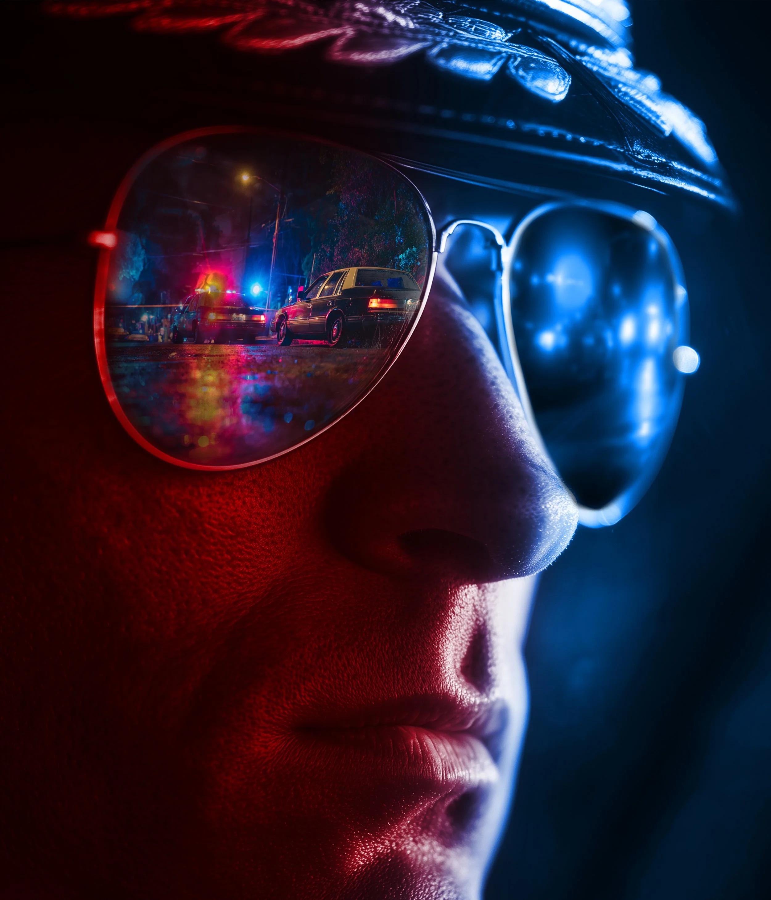 Close-up of a person's face wearing sunglasses reflecting police cars with flashing lights at night.
