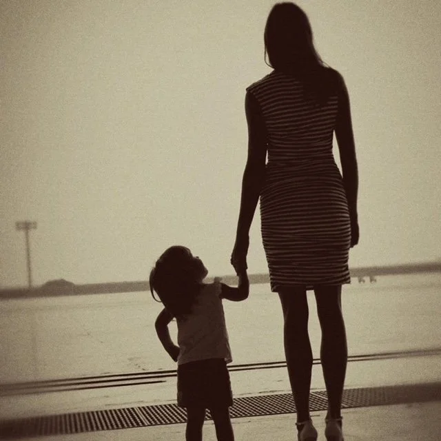 Silhouette of a military mom and daughter holding hands.