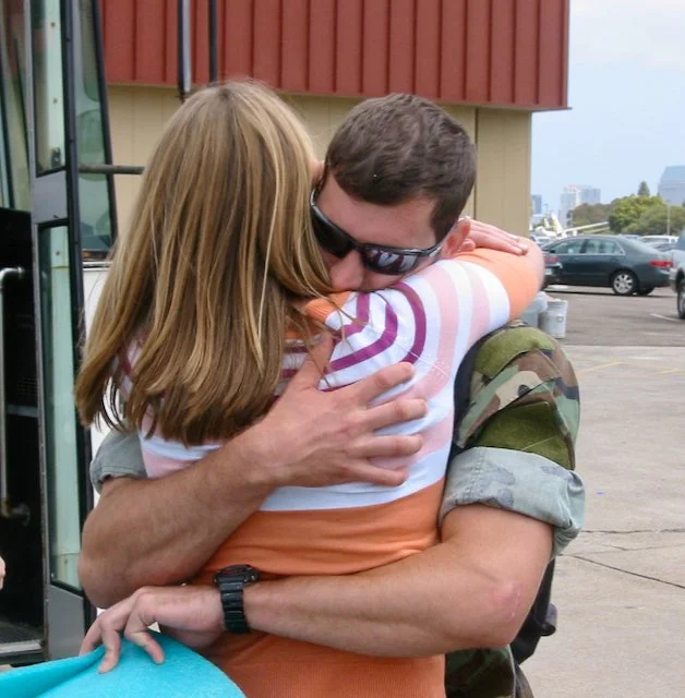 A Navy sailor in camies hugs his wife reuniting after a 7-month deployment.