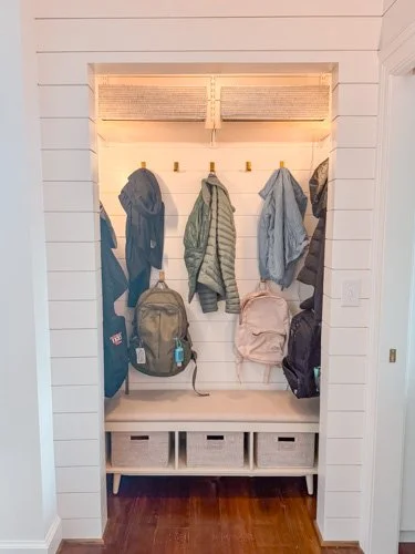 Mudroom with hooks holding jackets, backpacks, and a tote bag, and storage baskets below
