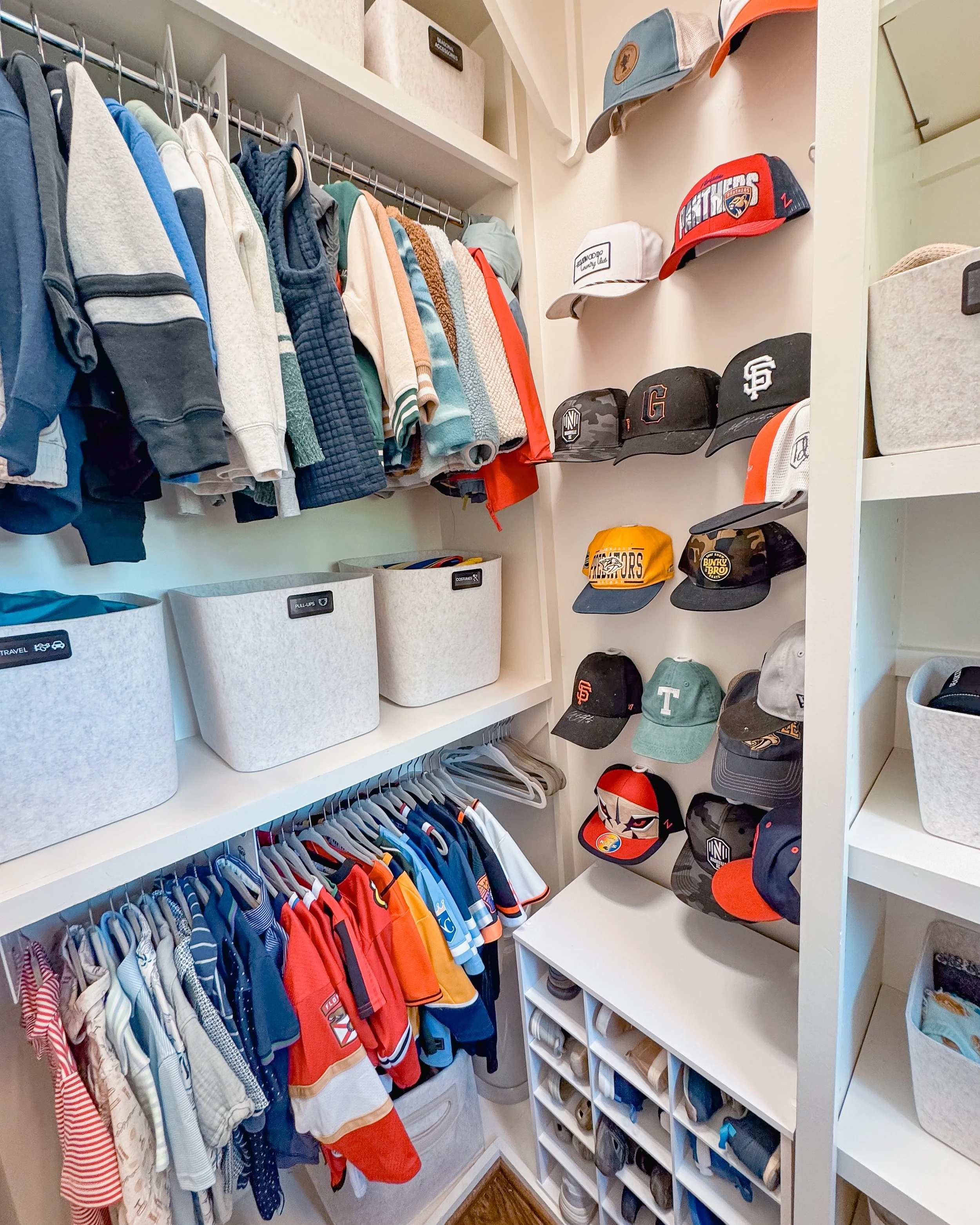 A well-organized closet with children's clothing, hats, and storage bins.