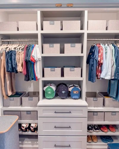 Organized closet with hanging clothes, backpacks, shoes, and storage bins.