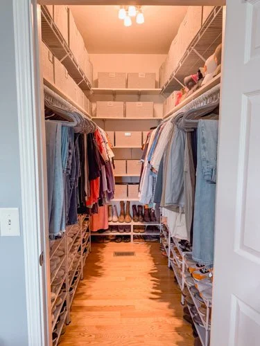 A walk-in closet with wire shelving filled with clothes, shoes, and storage boxes.