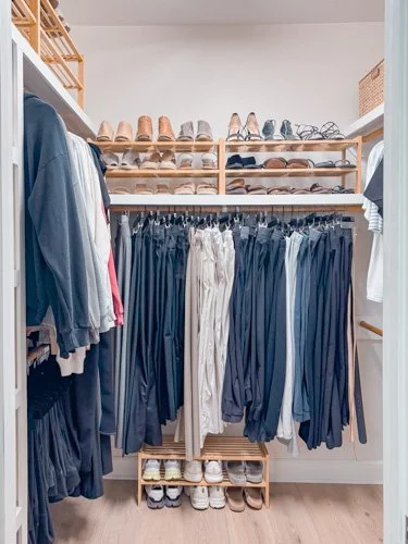 Walk-in closet with shoes on shelves, and clothing hanging on rods