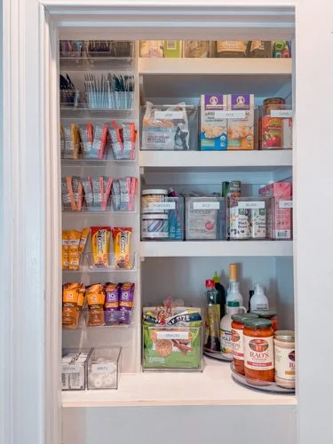 Pantry shelf with snack bags on left, canned and boxed foods on right, and various jars and bottles on the bottom shelf.