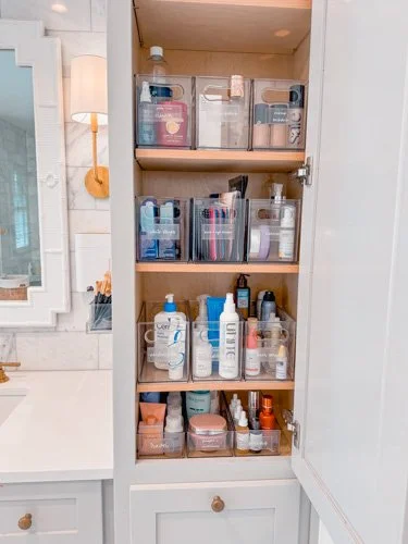 Bathroom cabinet with shelves holding toiletries, skincare products, and personal care items.