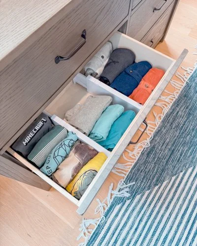 Open dresser drawer with neatly folded socks and underwear in various colors.