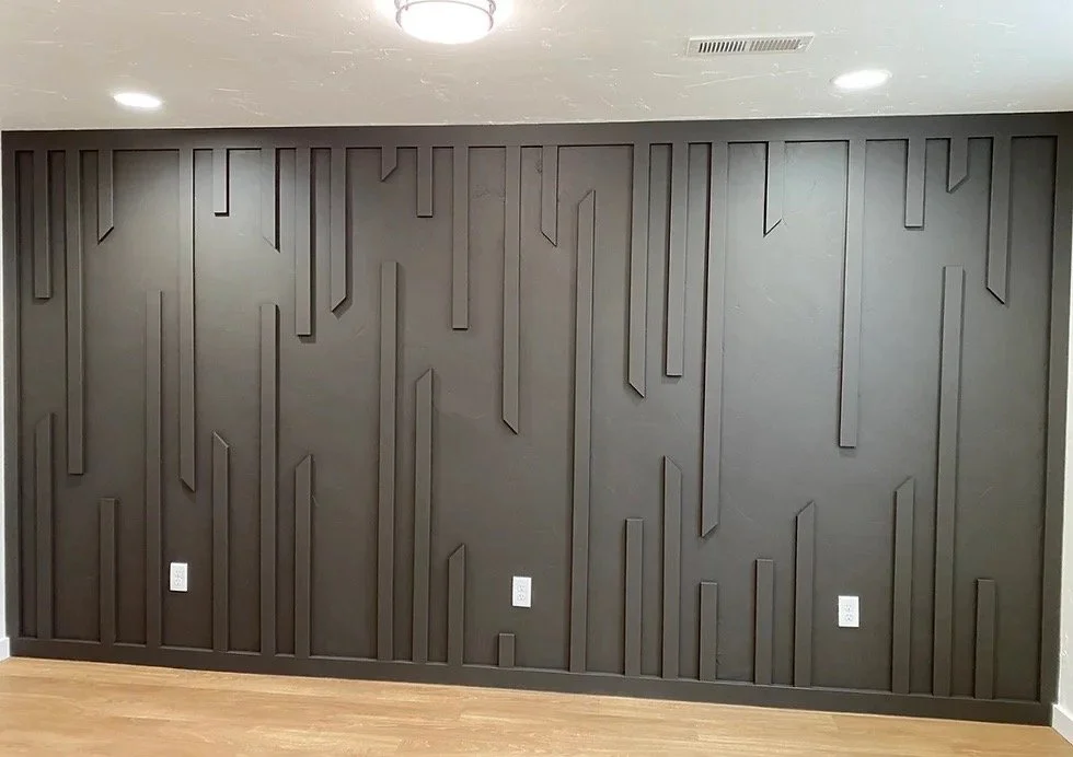 Interior wall painted dark gray with geometric, linear textured patterns, three electrical outlets near the bottom, and ceiling lights.