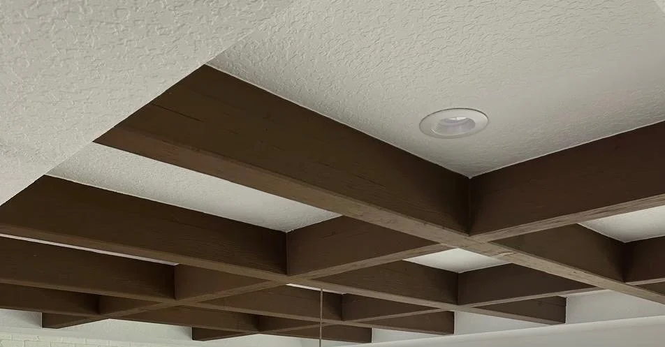 Ceiling with wooden beams and a round recessed light fixture.