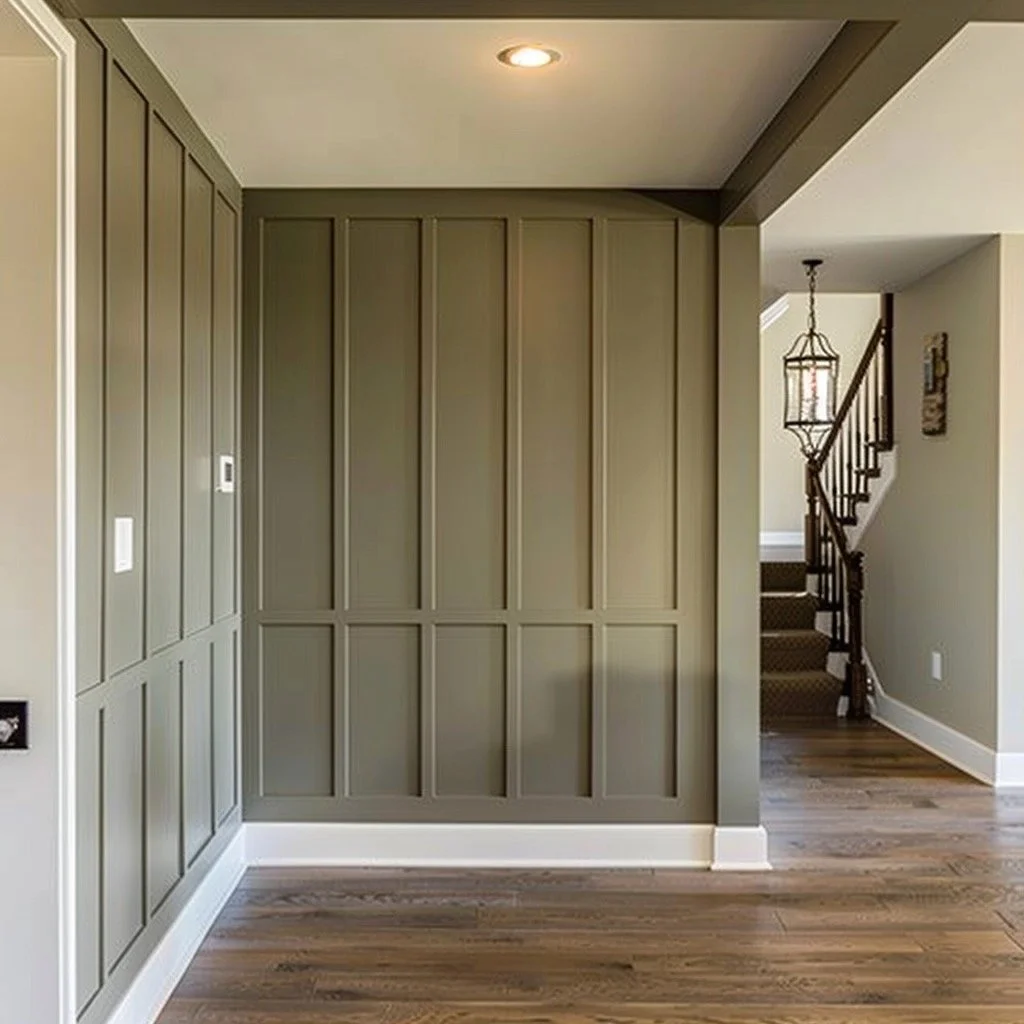 Interior view of a room with green wainscoting walls, hardwood flooring, and a staircase with a decorative lantern hanging. The ceiling has a recessed light.