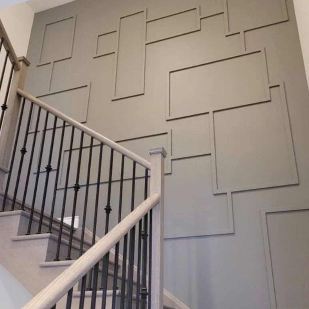 Interior view of a staircase with a modern decorative accent wall featuring various-sized rectangular wall panels.
