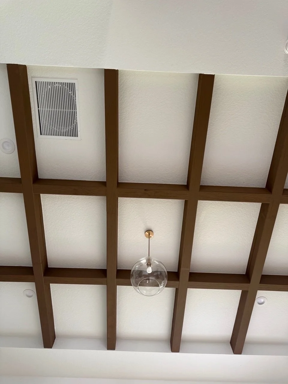 Ceiling with wooden beams, a hanging glass globe light fixture, an air vent, and recessed ceiling lights.