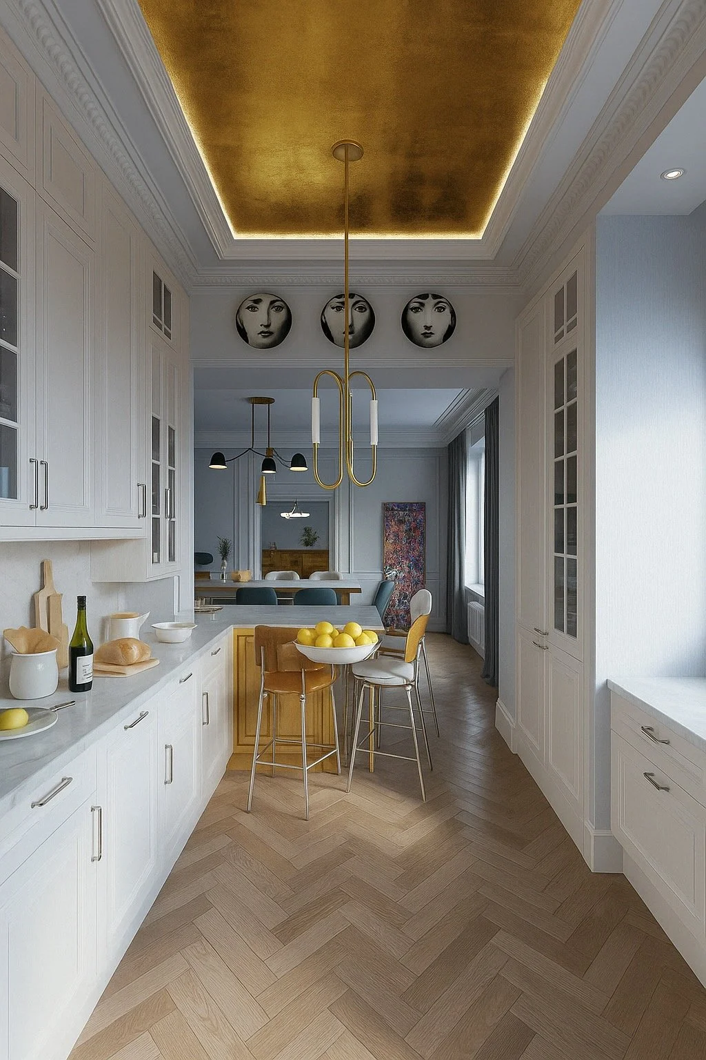 Modern kitchen with white cabinets, a gold ceiling detail, and pendant lighting. There are bar stools around a small table with lemons, and artwork with faces on the wall.