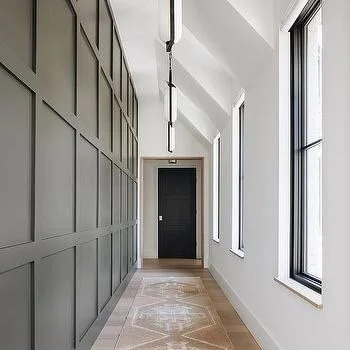 Bright hallway with gray paneled wall, large windows, and light-colored rug.