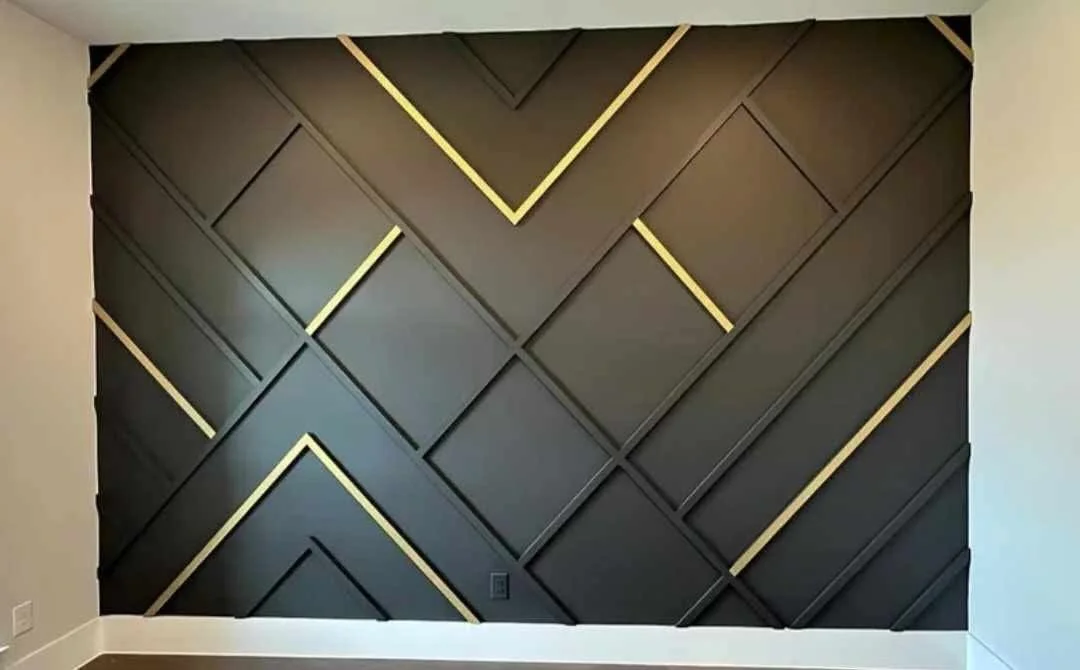 Decorative wall with black panels arranged in a geometric pattern accented by gold lines.