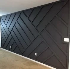 Black wall with geometric diagonal patterns and a small white light switch
