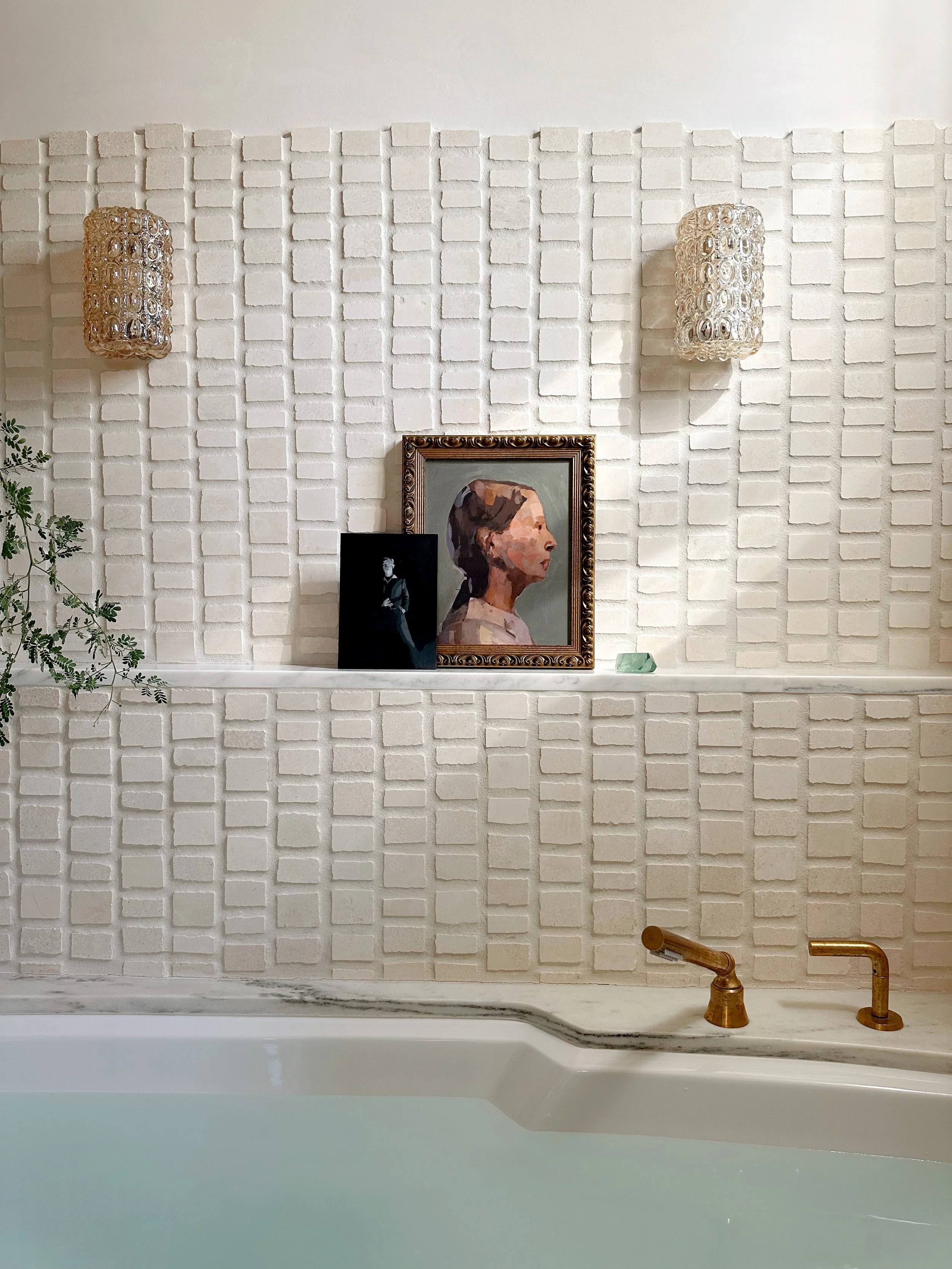 original oil paintings rest comfortable on a marble ledge flanked by vintage sconces