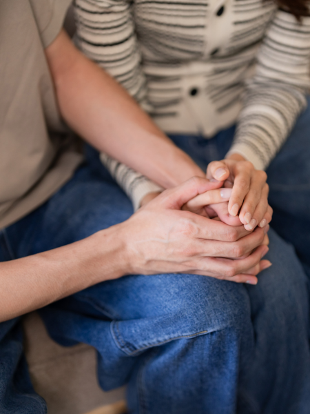 Two people holding hands, one person's hand gently grasping the other's hand.