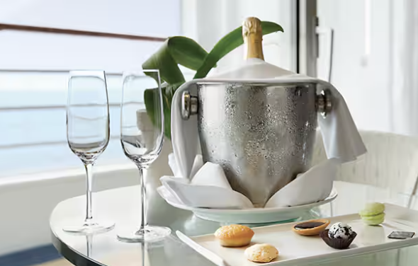 A table set for celebrating with a champagne bucket and glasses, and a plate of assorted macarons.